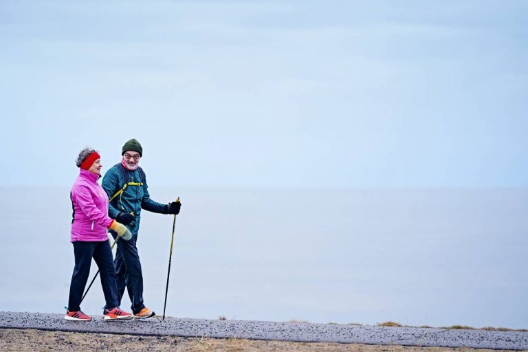 Vanhempi pariskunta ulkoilee meren rannassa.