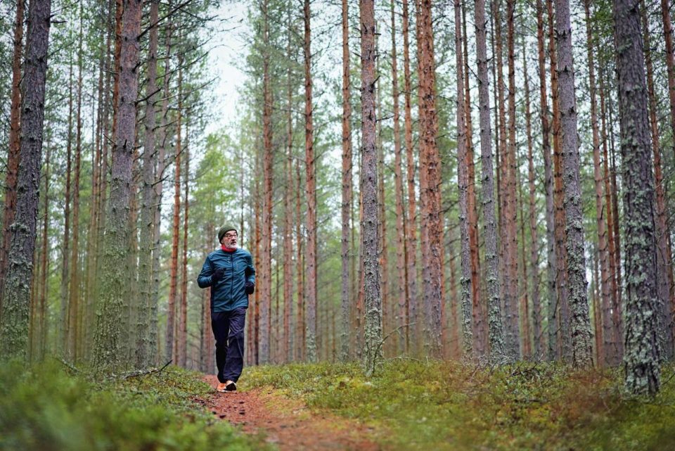 Mies lenkkeilee metsässä.