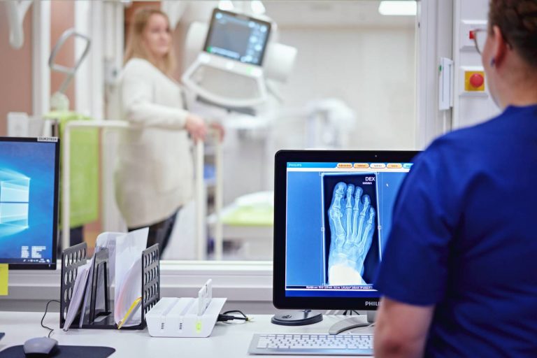 Röntgenhoitaja katsoo jalasta otettua röntgenkuvaa.