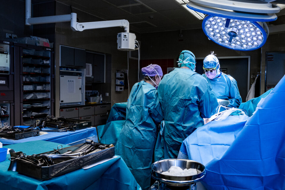 lääkäri ja hoitajat leikattavan potilaan ympärillä leikkaussalissa.