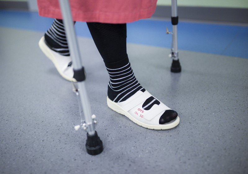 Potilas kävelee kyynärsauvojen avulla, kuvassa näkyy vain potilaan jalat kyynärsauvat.
