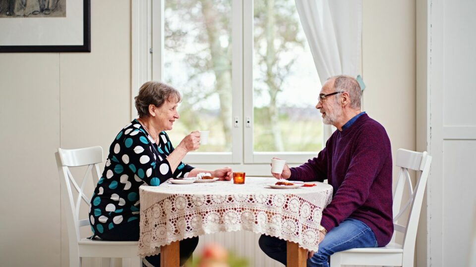 Kaksi ikäihmistä istuu pöydän ääressä.