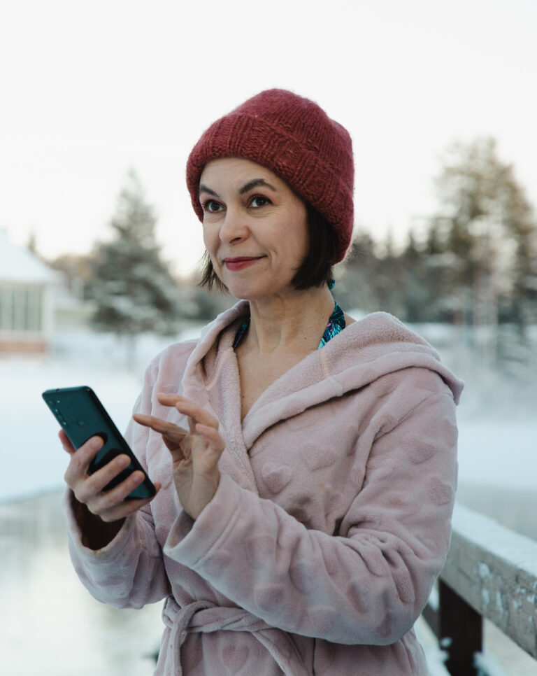 OmaPohteen mainos, jossa henkilö käyttää puhelinta aamutakkipäällä talvella pihalla.