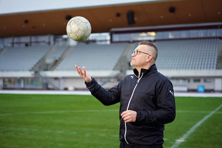 Mies pallon kanssa urheilustadionilla.