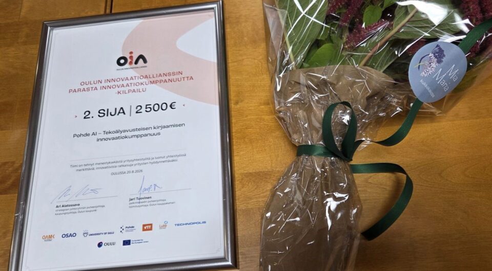 Diplomi ja kukkakimppu pöydällä.
