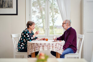Kaksi ikäihmistä kahvipöydän ääressä.