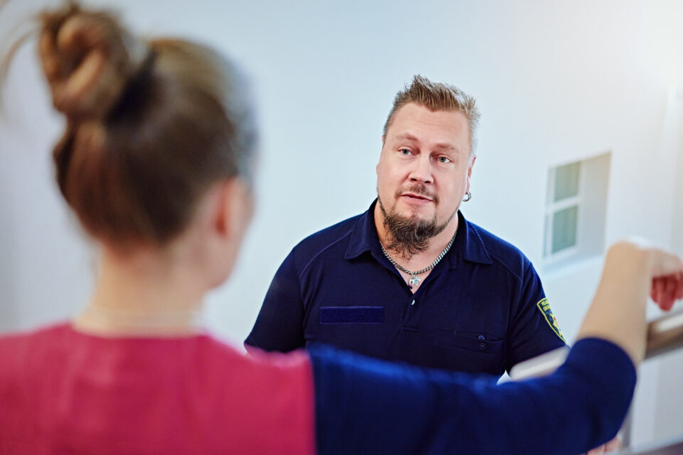 Kuvassa selin ammattilainen, joka ohjaa mies asiakasta.